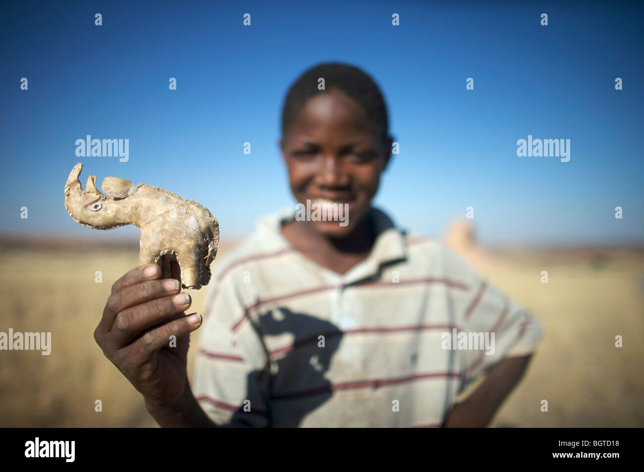 Close-up di ragazzo adolescente tenendo un rhino curio in cuoio, Kaokoland, Namibia Foto Stock