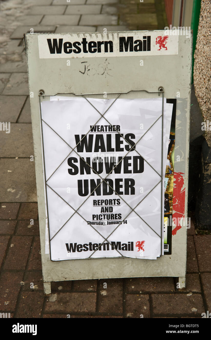 Il Galles nevicato sotto il giornale locale in primo piano sul bordo della strada al di fuori di giornalai in Newport South Wales UK Foto Stock