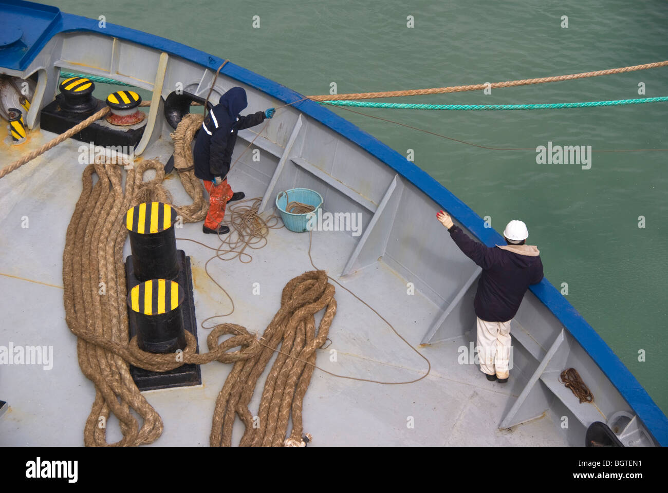 Personale di bordo sulla prua di una nave coinvolti nelle operazioni di ormeggio dopo l arrivo in porto. Foto Stock