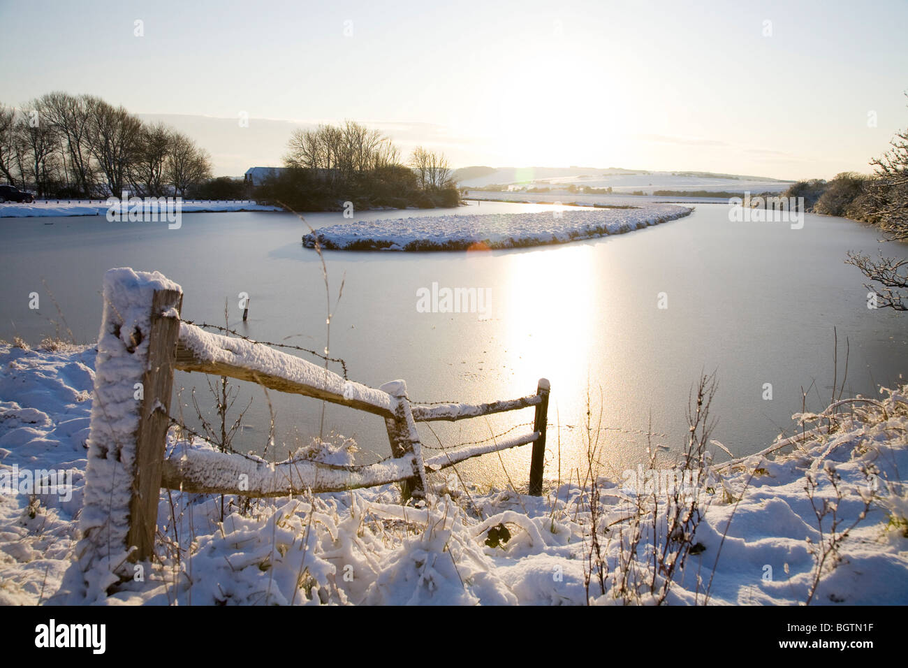 Una scena invernale a Cuckmere Valley della coperta di neve la recinzione, Frozen River e sole. Foto Stock