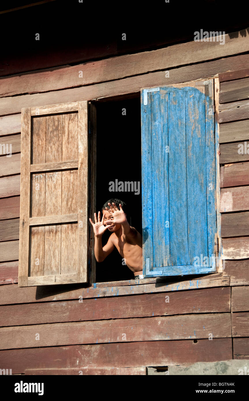 Ragazzo sventolano fuori una finestra del monastero in Siem Reap, Cambogia Foto Stock