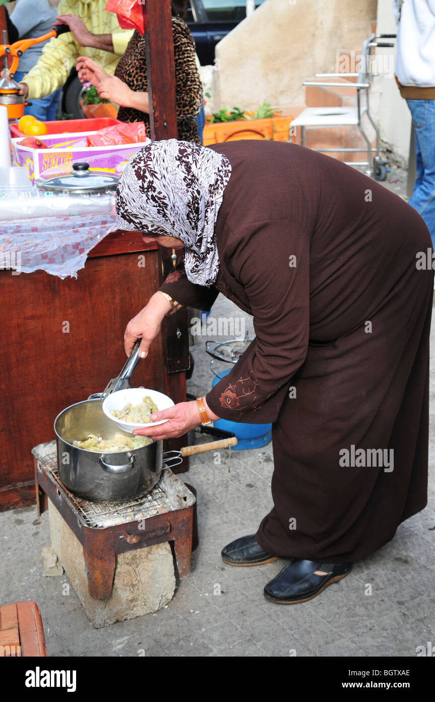 La donna araba serve cibo alla sua pressione di stallo Foto Stock