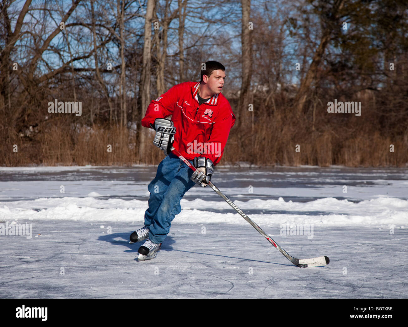 Ragazzo adolescente giocare ad hockey su un laghetto congelato Foto Stock