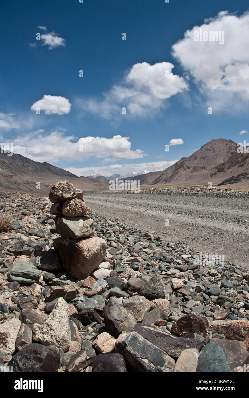 Vista di massi accatastati in prossimità di una strada vuota nel Pamir Highway altopiano vicino Murgab, Tagikistan Foto Stock