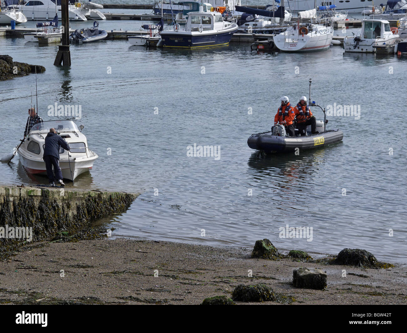 Una pattuglia di polizia barca aiuta a due pescatori che sono ripartiti nella loro piccola imbarcazione. Foto Stock