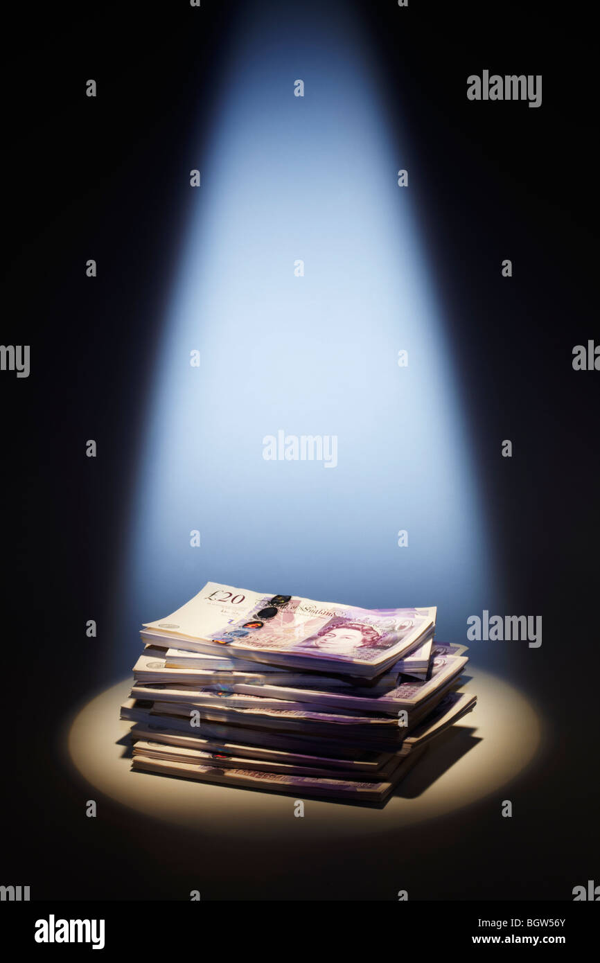 Pila di venti Pound note sotto i riflettori Foto Stock