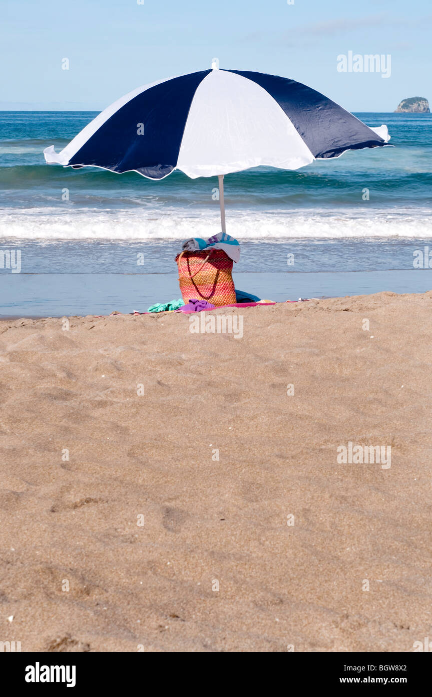 Borsa e ombrellone sulla spiaggia con asciugamani Foto Stock