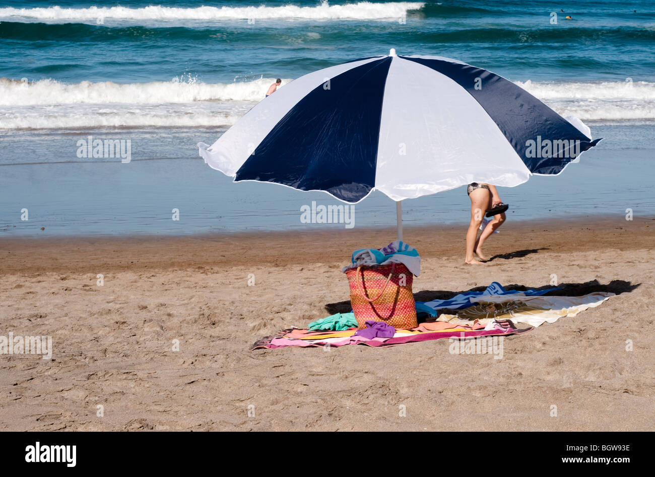Borsa e ombrellone sulla spiaggia con asciugamani Foto Stock