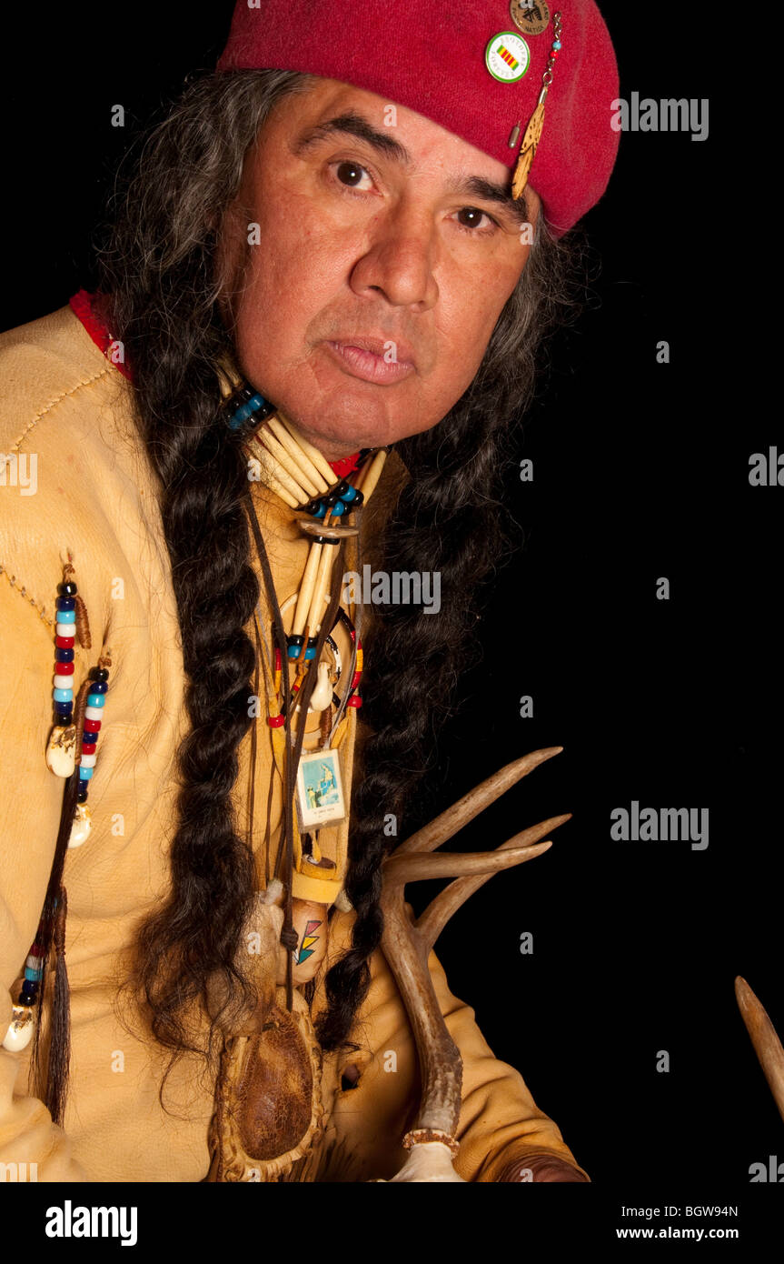 Native American Indian su sfondo nero con Red Hat lunghe trecce di indossare magliette di guarigione della pelle di cervo e il cranio di contenimento Foto Stock