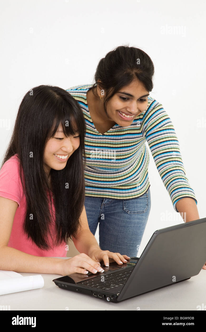 Asiatici e East Indian adolescenti cercando sorpreso da ciò che hanno trovato sul computer portatile Foto Stock