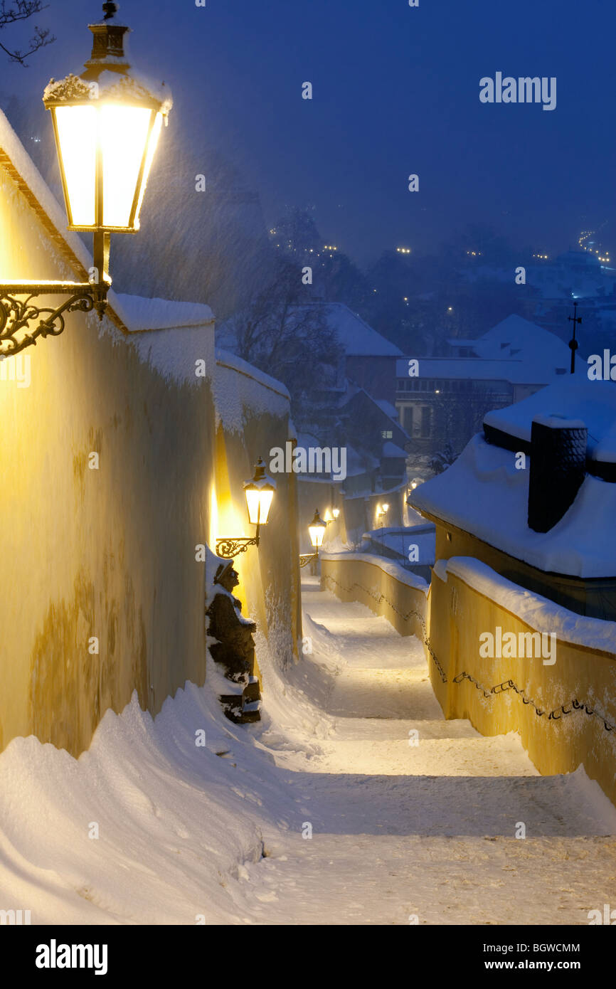 Scale strette da hradcany castello con lanterne a gas durante la nevicata Foto Stock