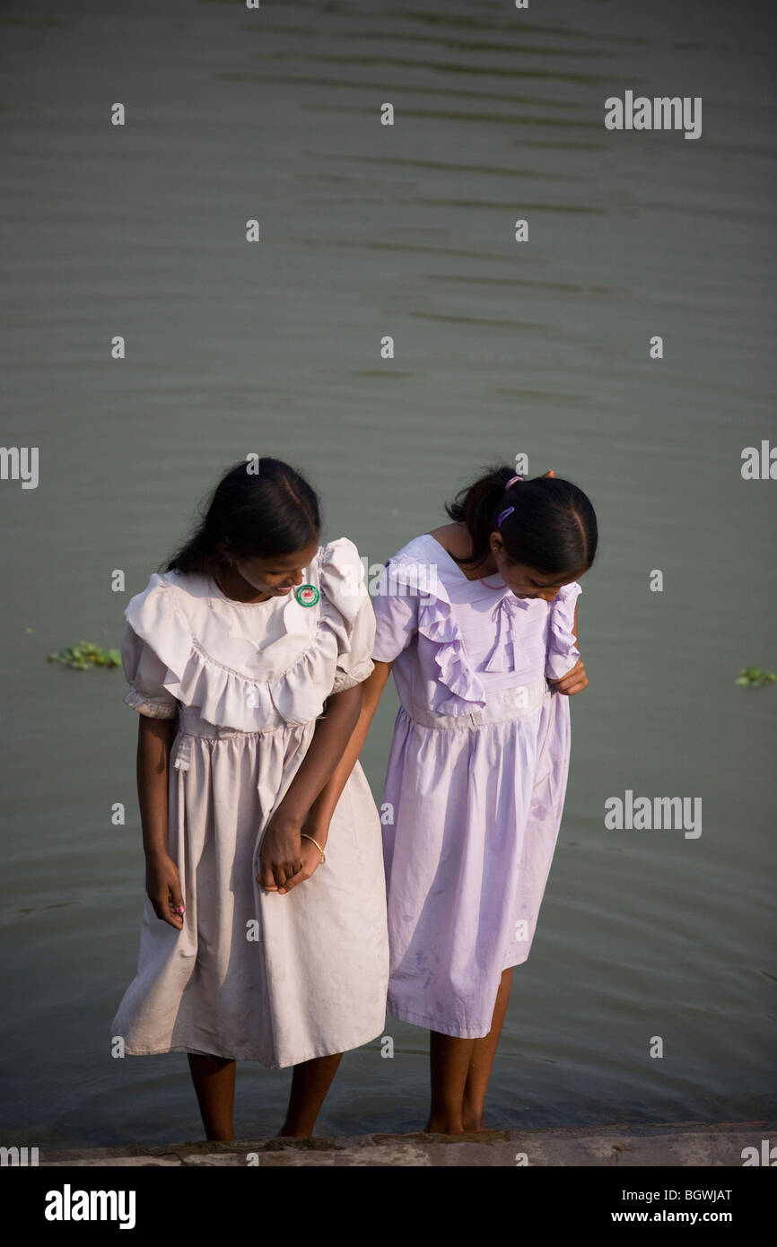 Due giovani sorelle bagnarsi i piedi in uno stagno in India Foto Stock
