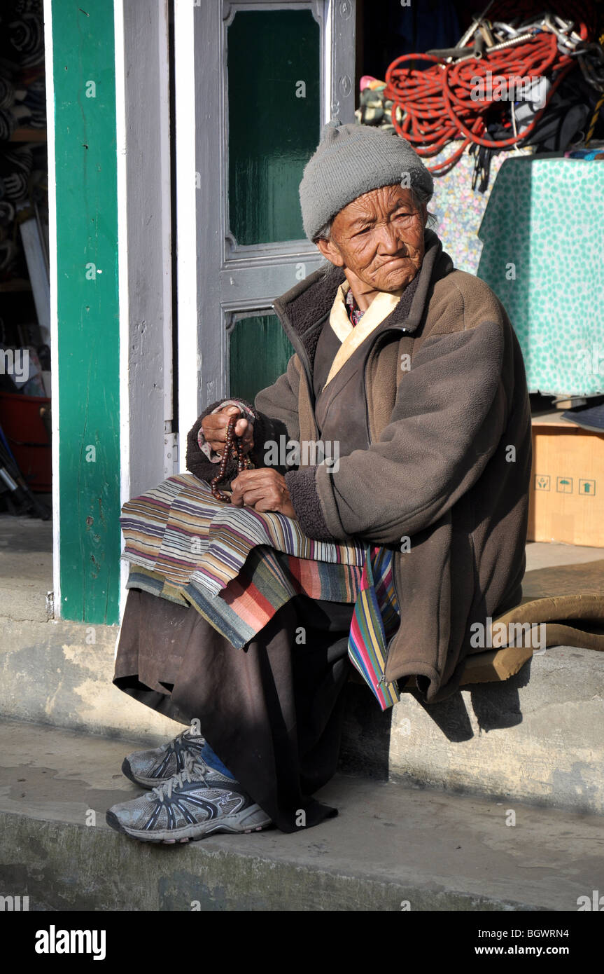 Vecchia Signora Nepalese con la preghiera per la strada di Lukla, Nepal sul sentiero di Everest, eseguendo i grani di preghiera attraverso le sue mani. Foto Stock