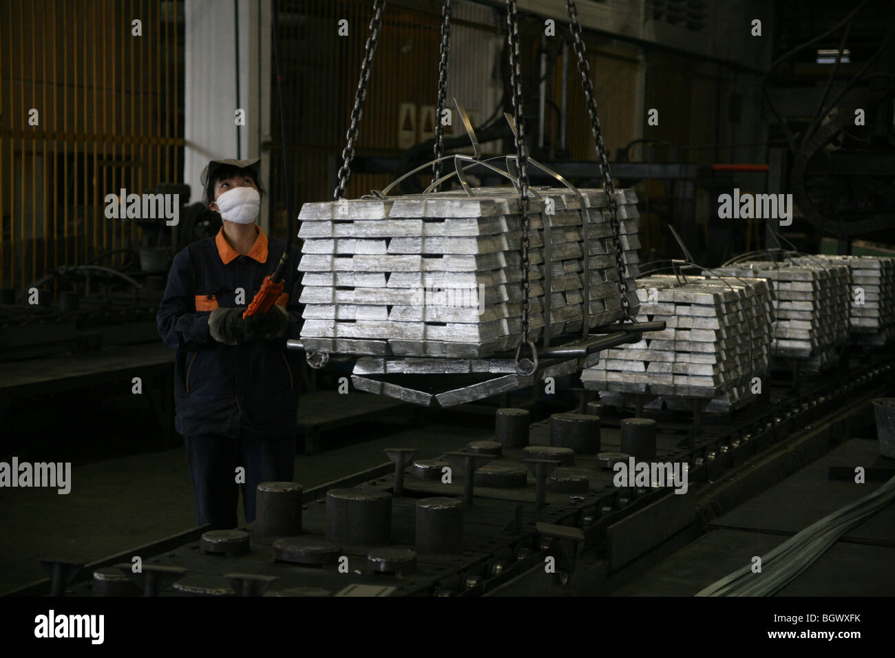 Lavoratore cinese di sollevamento lingotti di zinco Foto Stock