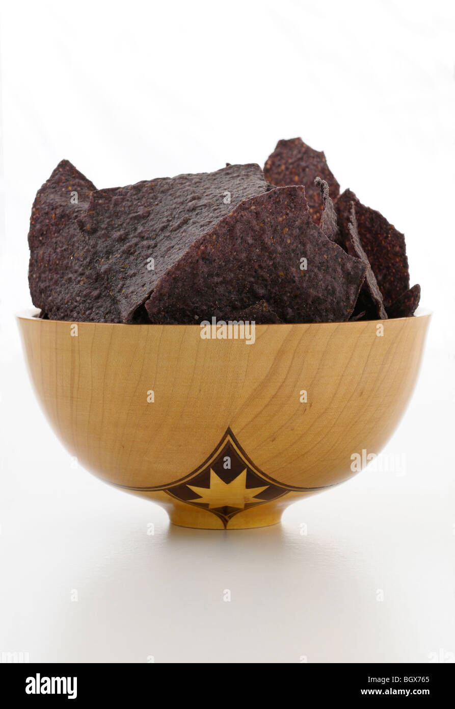 In legno fatti a mano rivolta ciotola riempita con blue corn chips su bianco Foto Stock