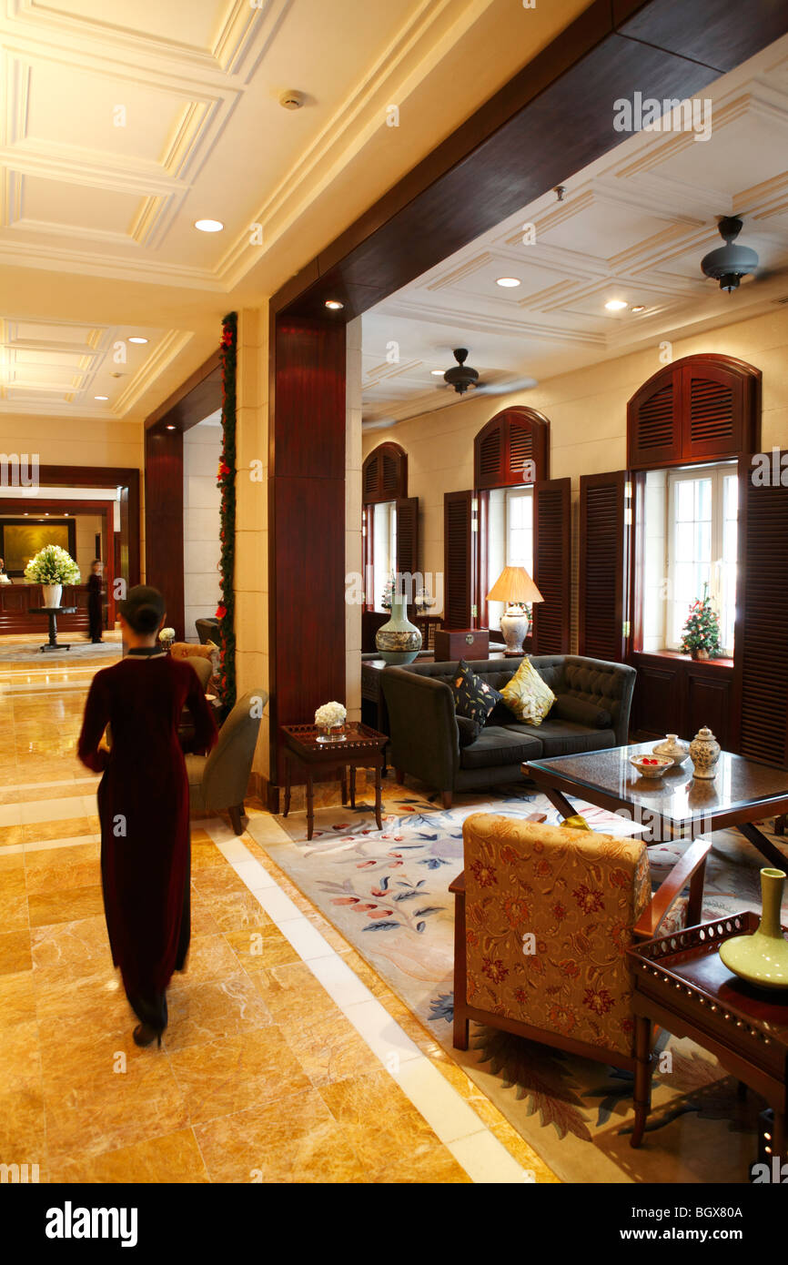 Rapporti con gli ospiti il personale a piedi attraverso la lobby dell'Hotel Metropole Hanoi, Vietnam. Foto Stock