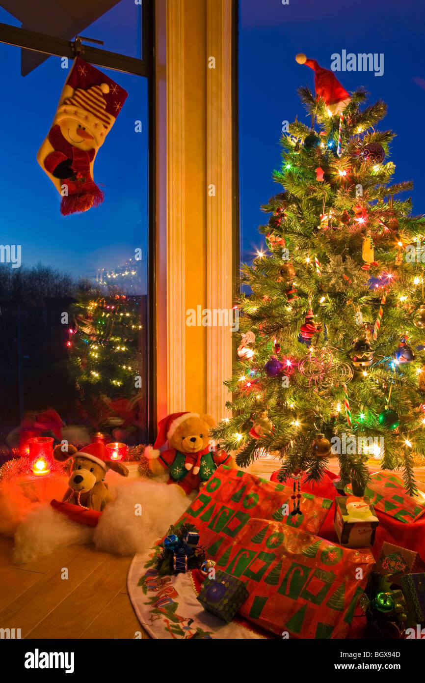 Albero di Natale con le luci, decorazioni, doni e una calza di Natale appesi in una finestra al tramonto, gli artisti punto, Hyde Foto Stock