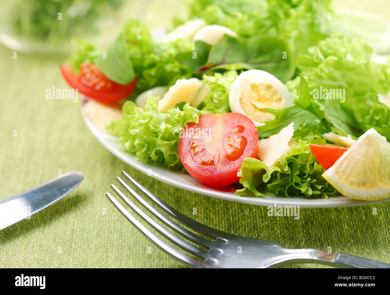 Insalata fresca con pomodoro e uova di quaglia in una ciotola bianco su una tovaglia verde Foto Stock