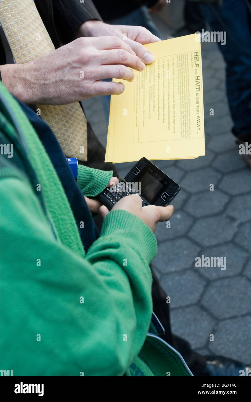 Un Newyorkese in Union Square invia un messaggio di testo come una donazione per fornire fondi per aiuti ad Haiti Foto Stock