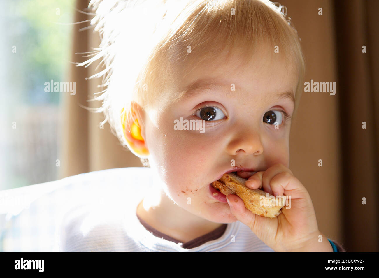 Baby boy a mangiare una fetta di pane Foto Stock