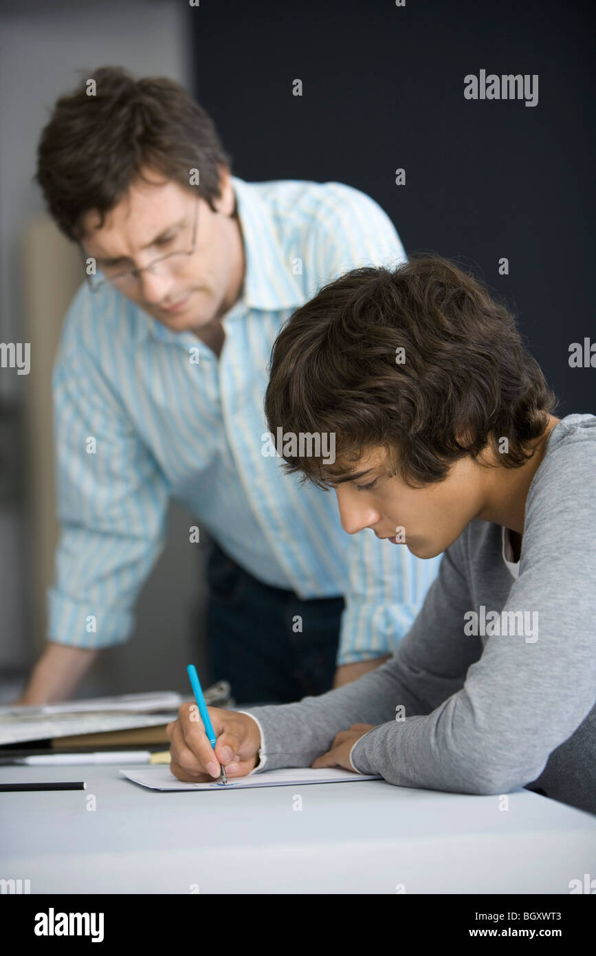 Studente di College lavorando su assegnazione, insegnante assistere Foto Stock