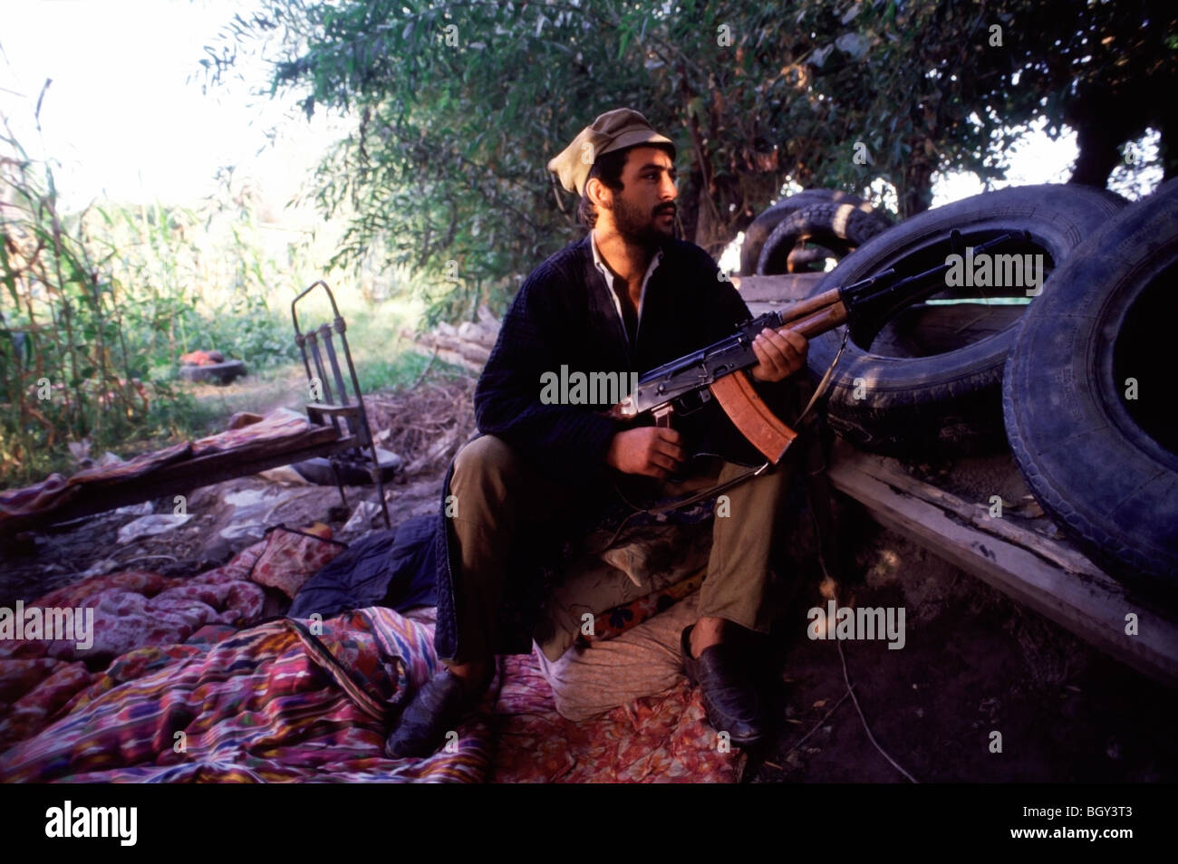 Un pro-Nabiyev Tajik con il suo fucile Kalashnikov siede sulla linea del fronte del conflitto etnico in Tagikistan nei primi anni novanta Foto Stock