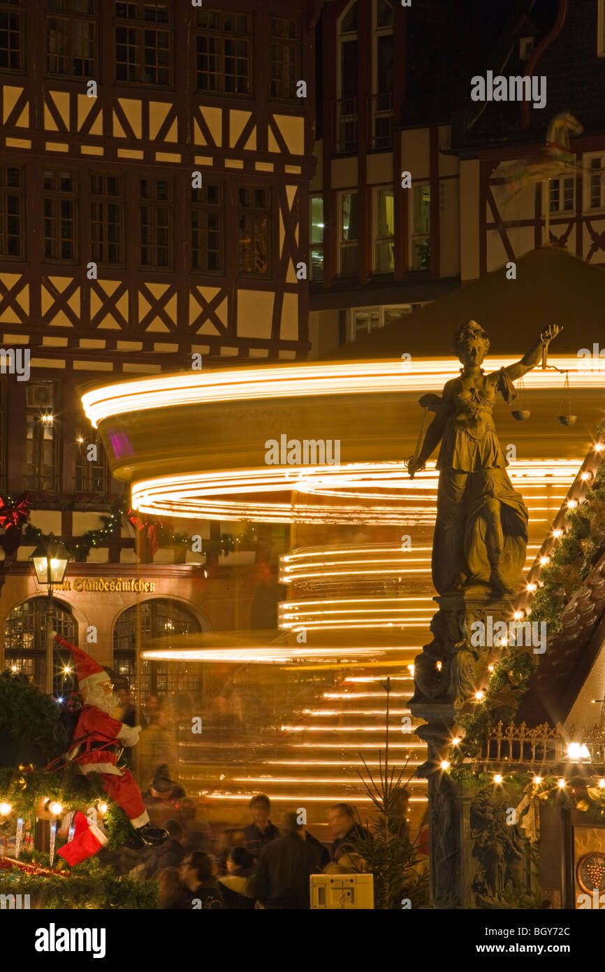 Christkindlmarkt (Mercatino di Natale) scena con un merry-go-round impostare di fronte agli edifici in Römerberg (Piazza del Municipio) Foto Stock