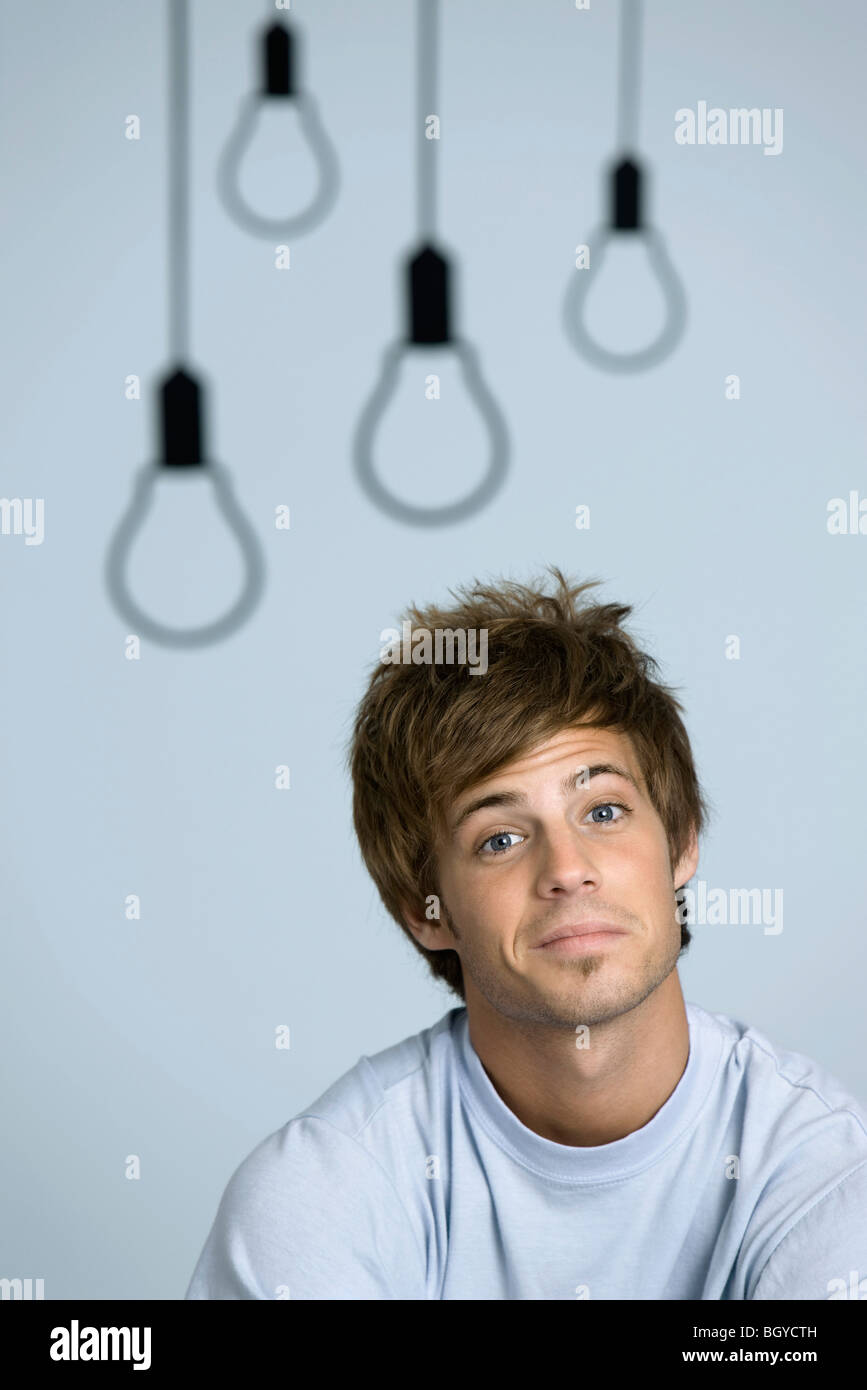 Giovane uomo sorridente in telecamera, le sopracciglia sollevate Foto Stock