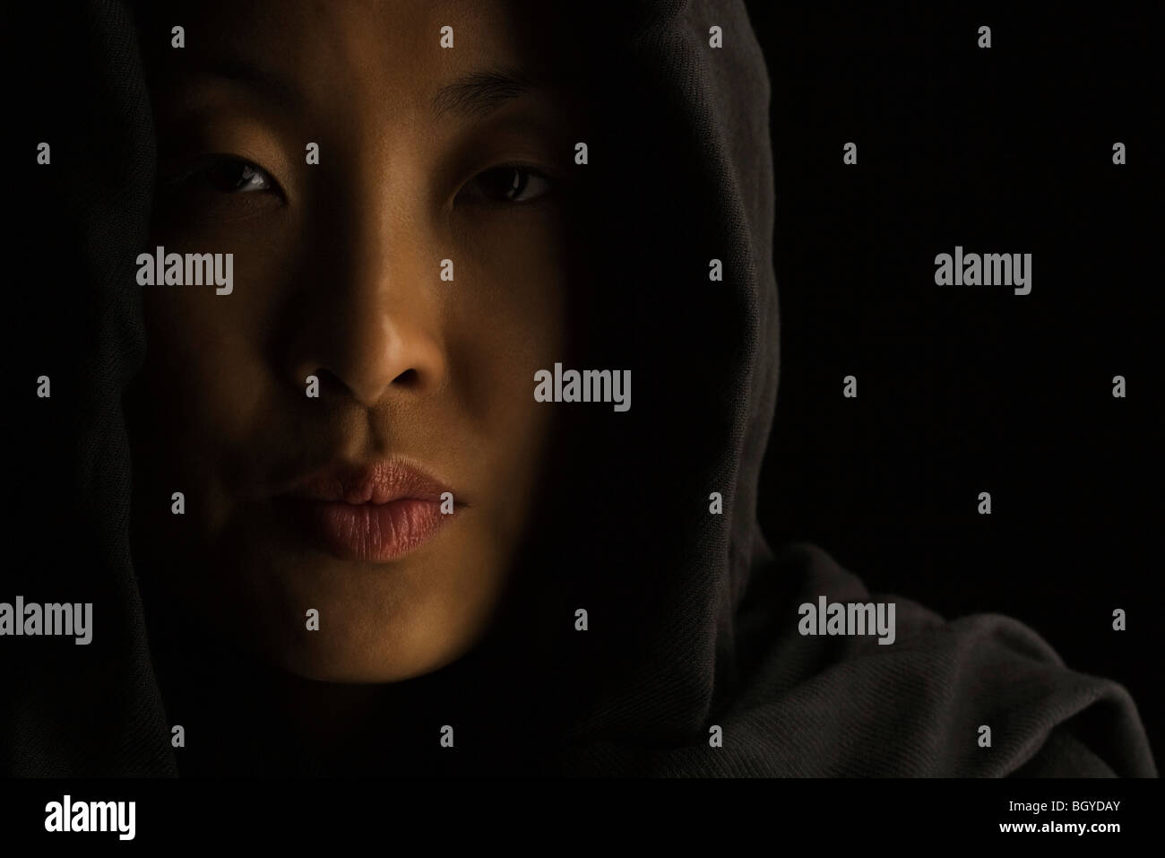 Donna che indossa il cofano, guardando la fotocamera con pursed lips Foto Stock