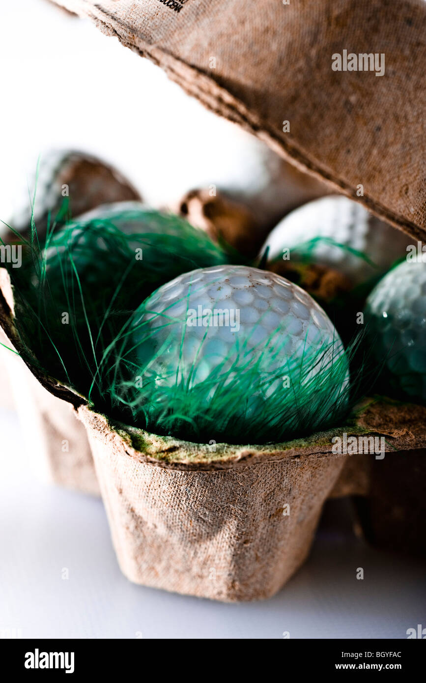 Concetti alimentari, palline da golf e di erba artificiale in confezione di uova Foto Stock