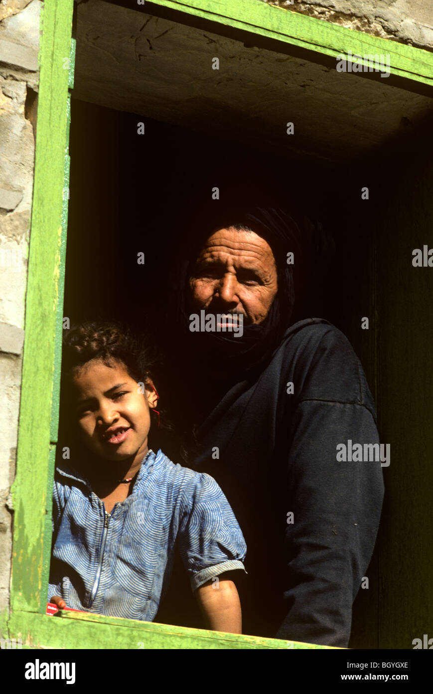 Padre e figlio in posa nella finestra delle loro sgangherate casa di villaggio all'interno di Mauritania. Foto Stock