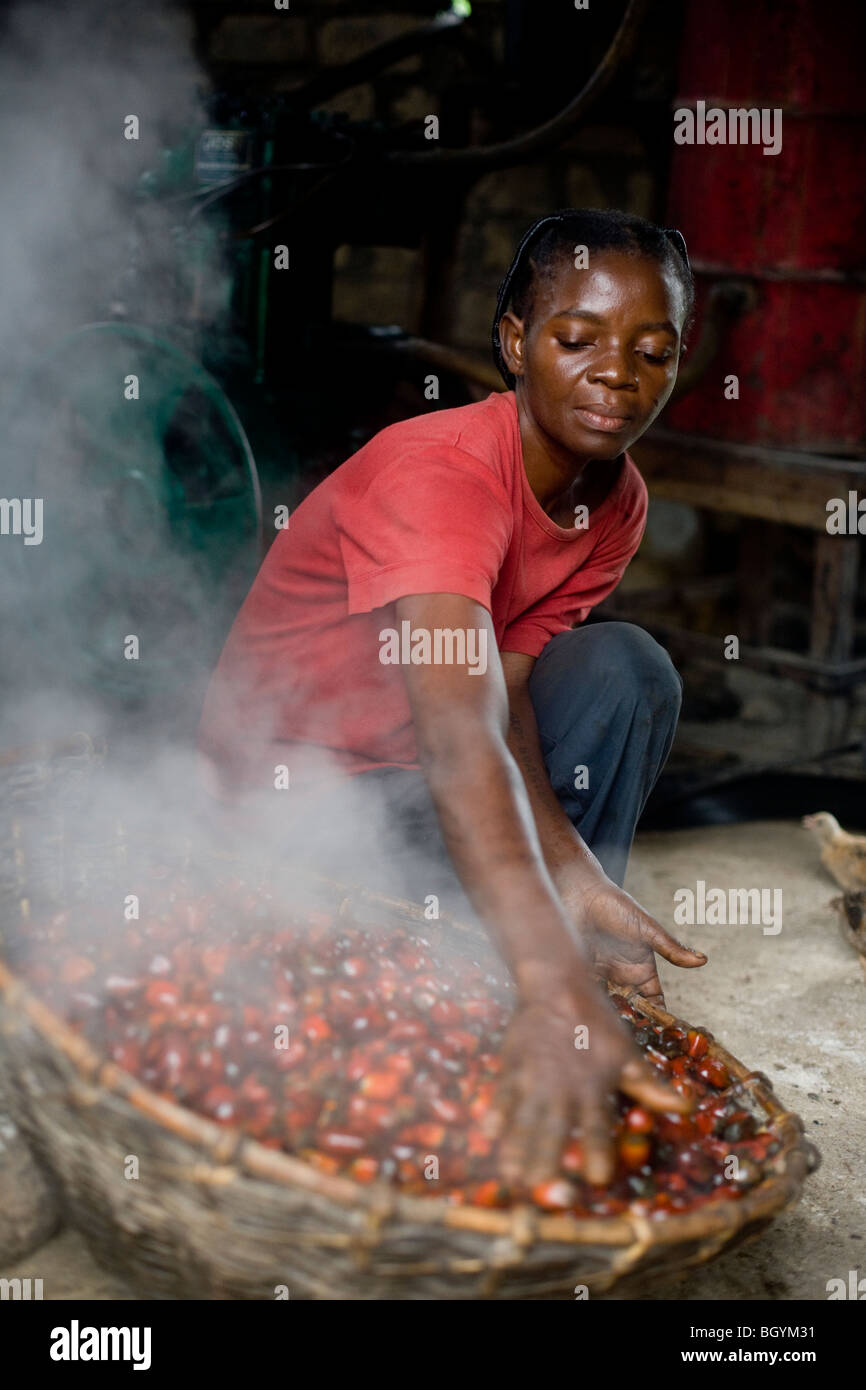 Agricoltore operante per la cottura a vapore di olio di palma Foto Stock