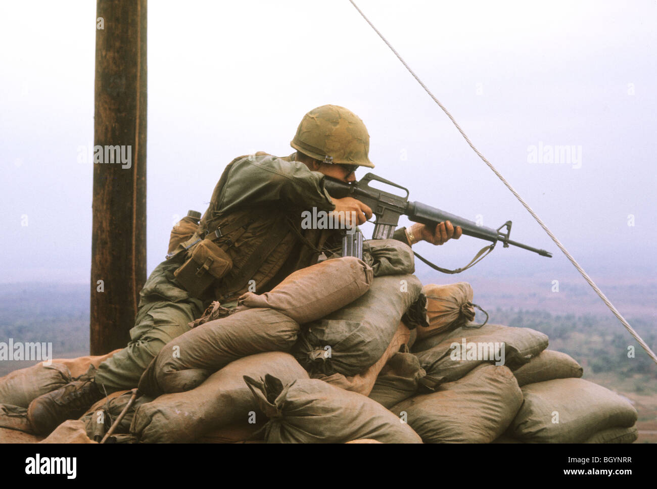 Un soldato della quarta divisione di fanteria Ivy punti un M-16 fucile dalla cima di Monte del Drago durante la Guerra del Vietnam nei primi mesi del 1968 Foto Stock