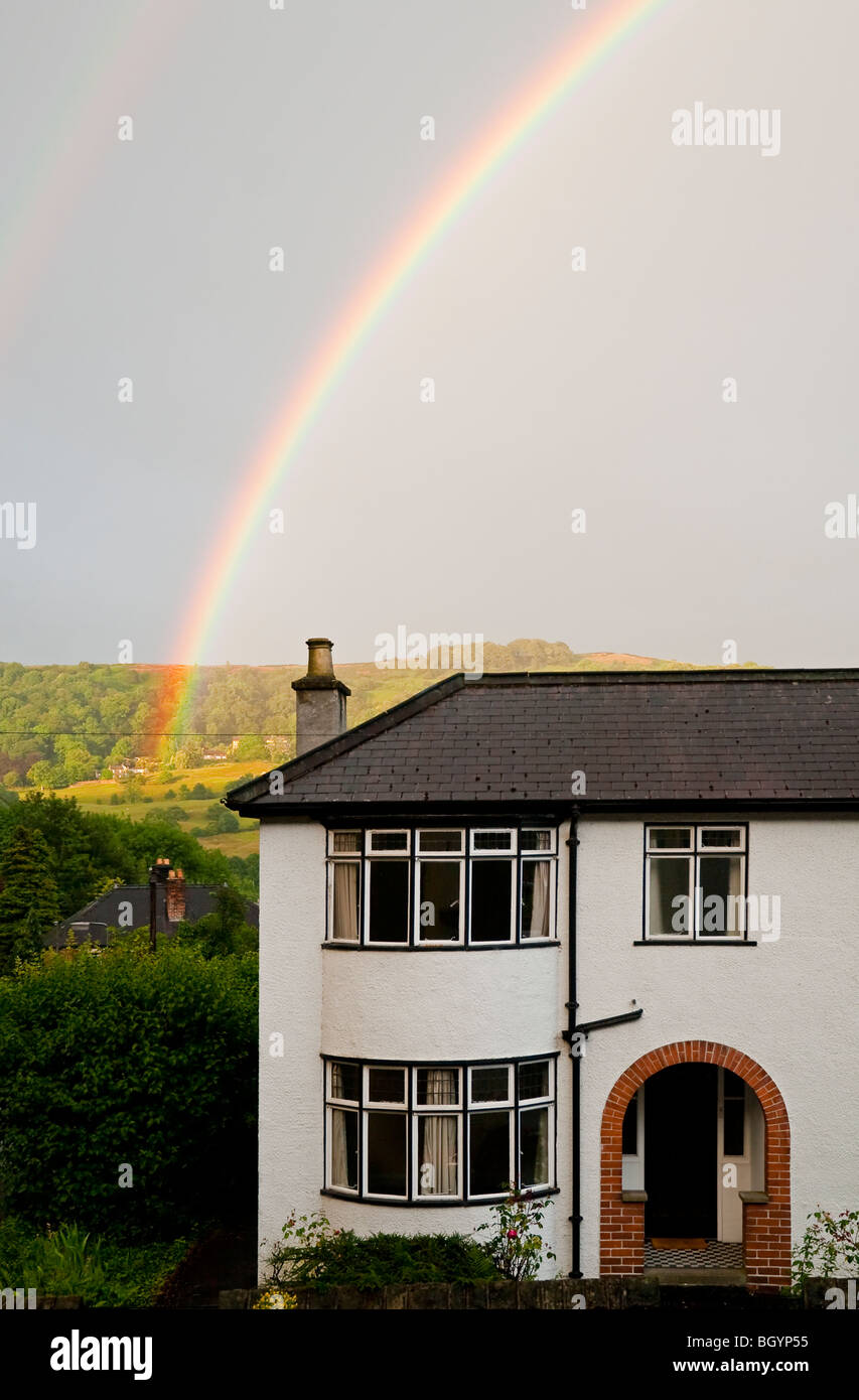 Rainbow oltre ad arco casa suburbana con colline in lontananza Foto Stock