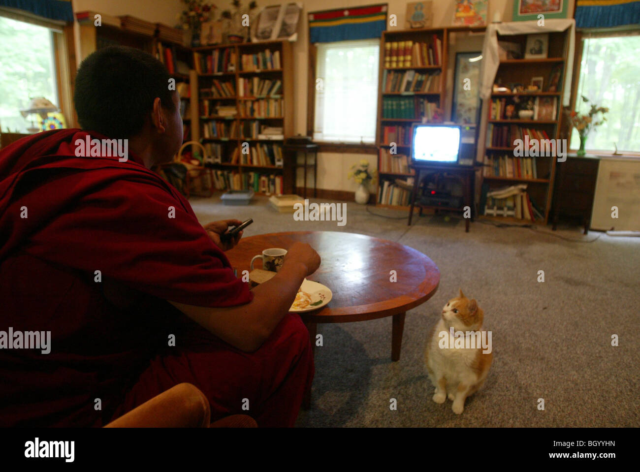 Un tibetano monaco buddista guarda la televisione prima di intestazione per un lavoro. Foto Stock