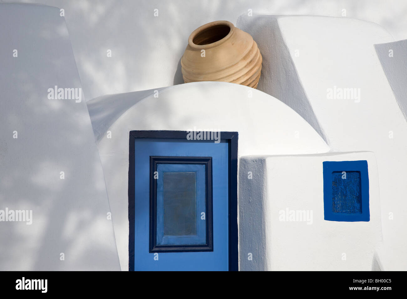 Tipica isola greca dimora imbiancata con vaso di argilla su porta e finestra blu a Oia, Santorini, Grecia Foto Stock