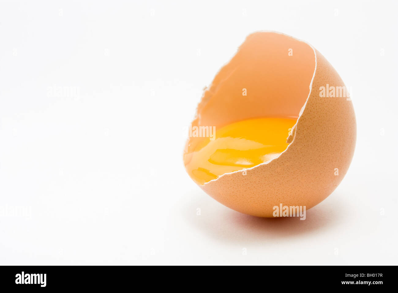 Unico crepe aperte di uova di galline che mostra il tuorlo isolata contro uno sfondo bianco Foto Stock