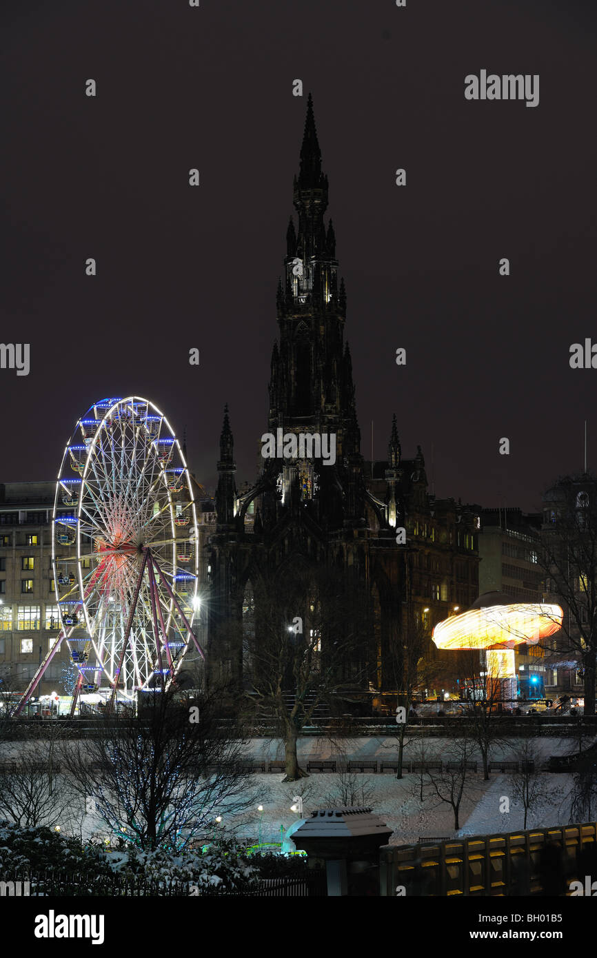 Monumento di Scott affiancato da Natale grande ruota panoramica Ferris e carosello in Princes Street Gardens, Edimburgo, Scozia, di notte Foto Stock