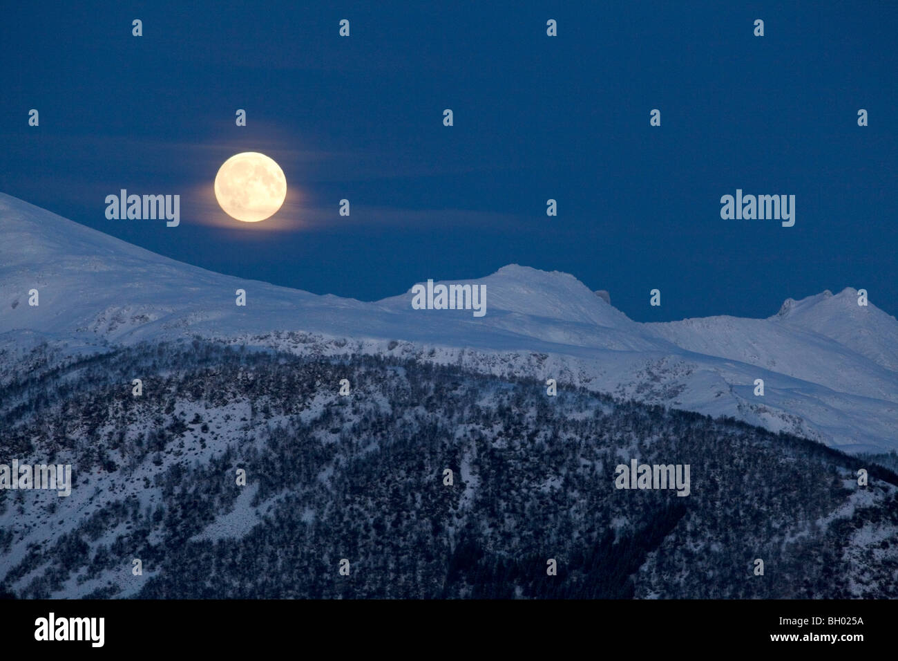 Luna piena sopra snowcovered mountain Foto Stock