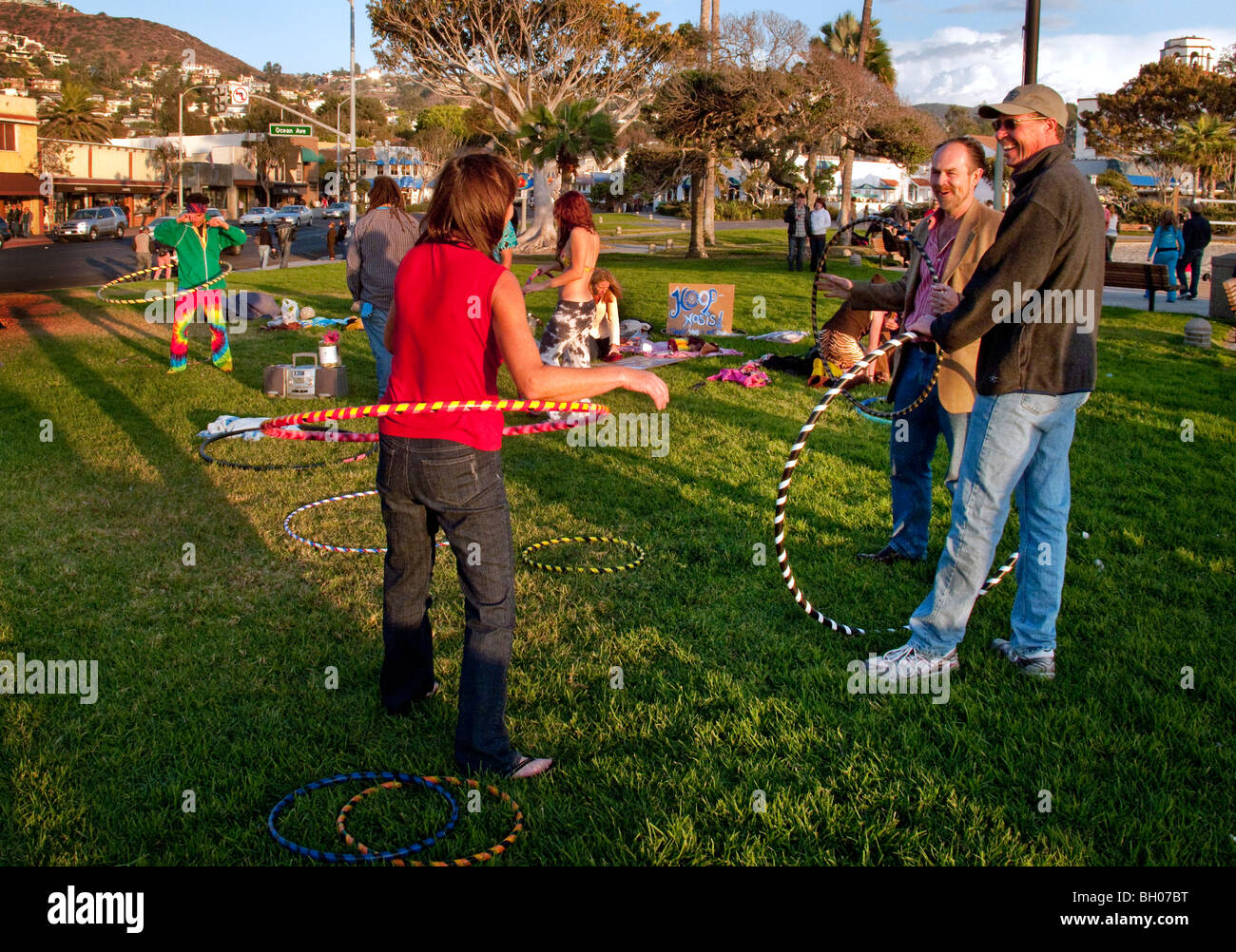 Felice hula hoop appassionati di tenere un 'Hoopnosis' sessione nel tardo pomeriggio di sole sulla spiaggia principale in Laguna Beach, CA. Foto Stock