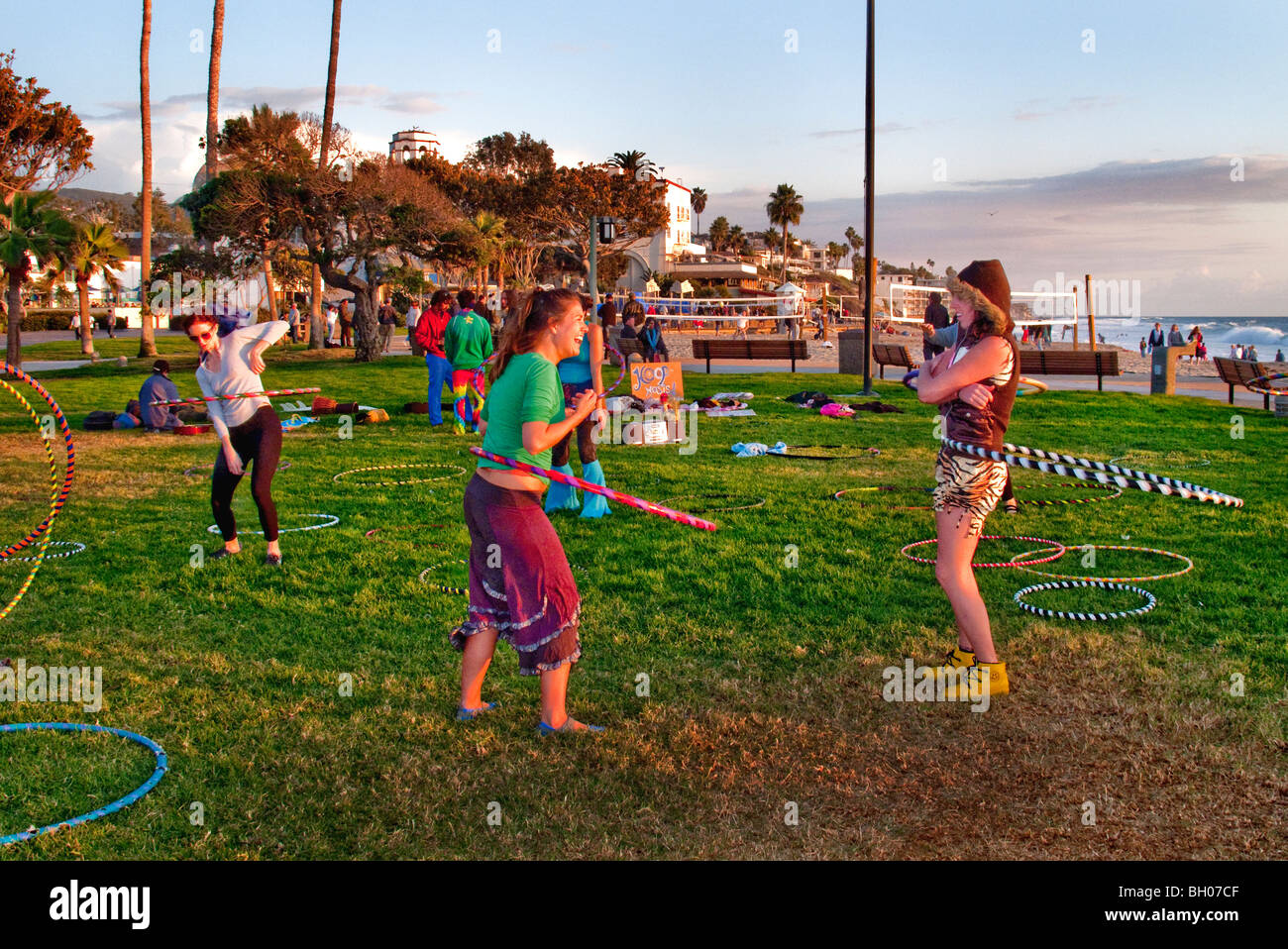 Felice hula hoop appassionati di tenere un 'Hoopnosis' sessione nel tardo pomeriggio di sole sulla spiaggia principale in Laguna Beach, CA. Foto Stock