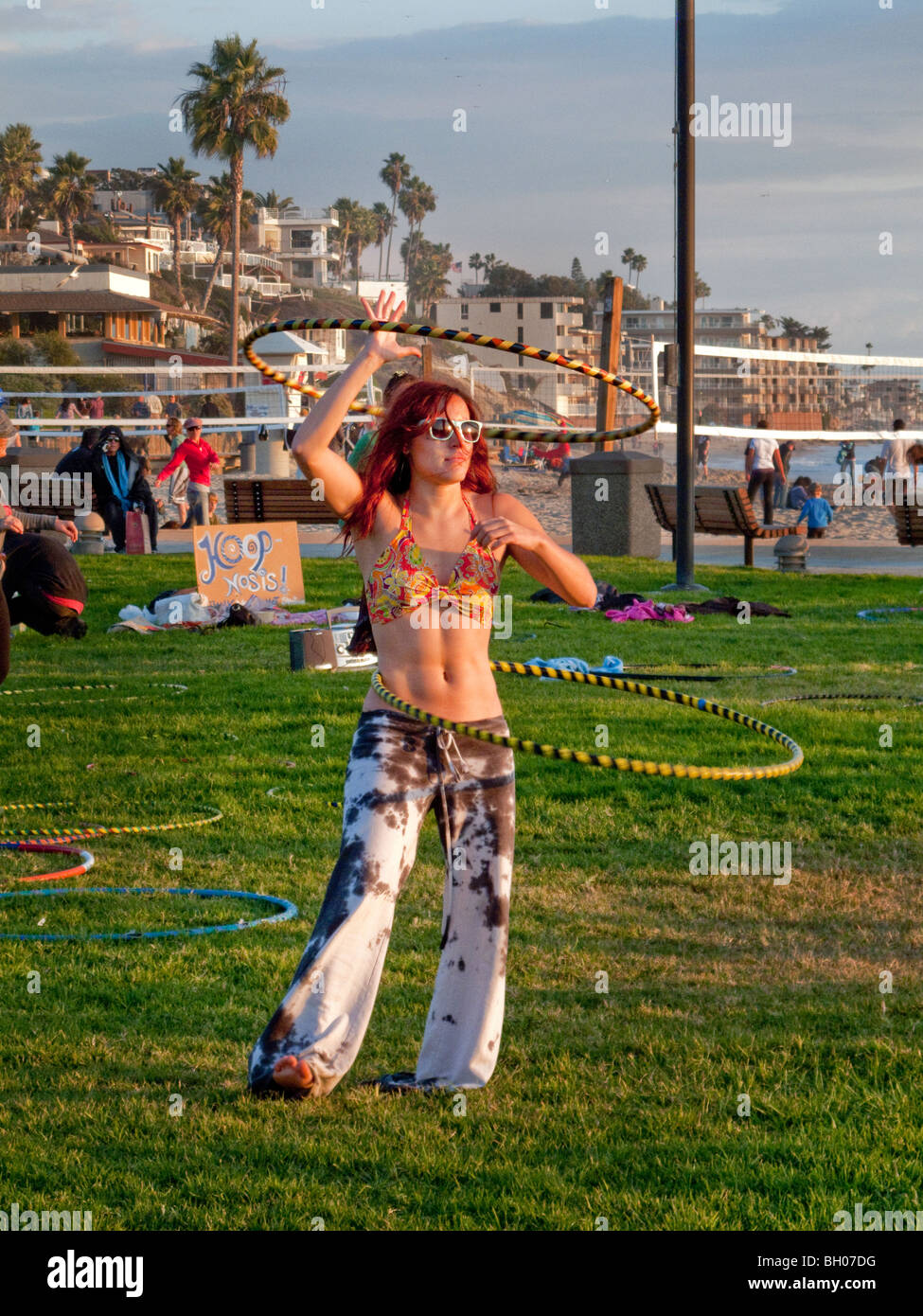 Un felice hula hoop entusiasta si unisce un 'Hoopnosis' sessione nel tardo pomeriggio di sole in Laguna Beach, CA. Nota segno. Foto Stock