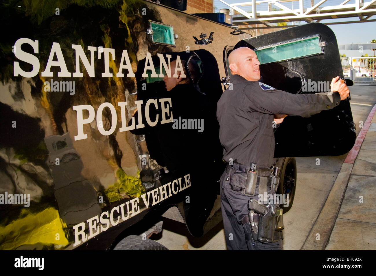 Un SWAT (Armi speciali e operazioni tattiche) del team ufficiale di polizia emerge da un blindato veicolo di soccorso in Santa Ana, California. Foto Stock