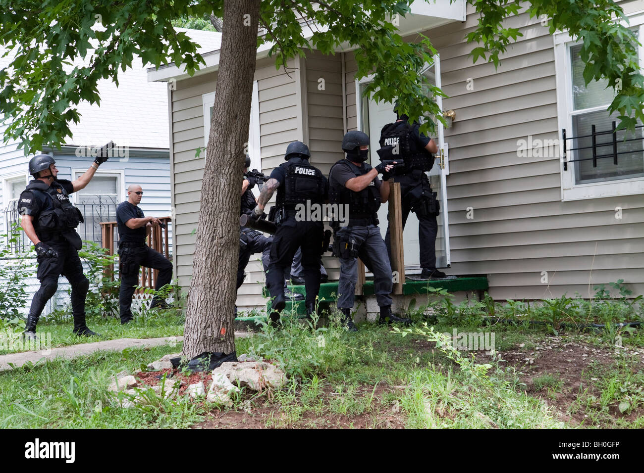 Polizia di tattiche di squadra rendendo entrata per servire un elevato rischio correlato al farmaco di un mandato di perquisizione. Street Unità narcotici. Foto Stock