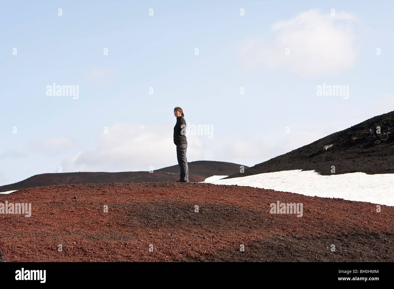 Donna in piedi nella lava su una collina, altipiani di Islanda Foto Stock