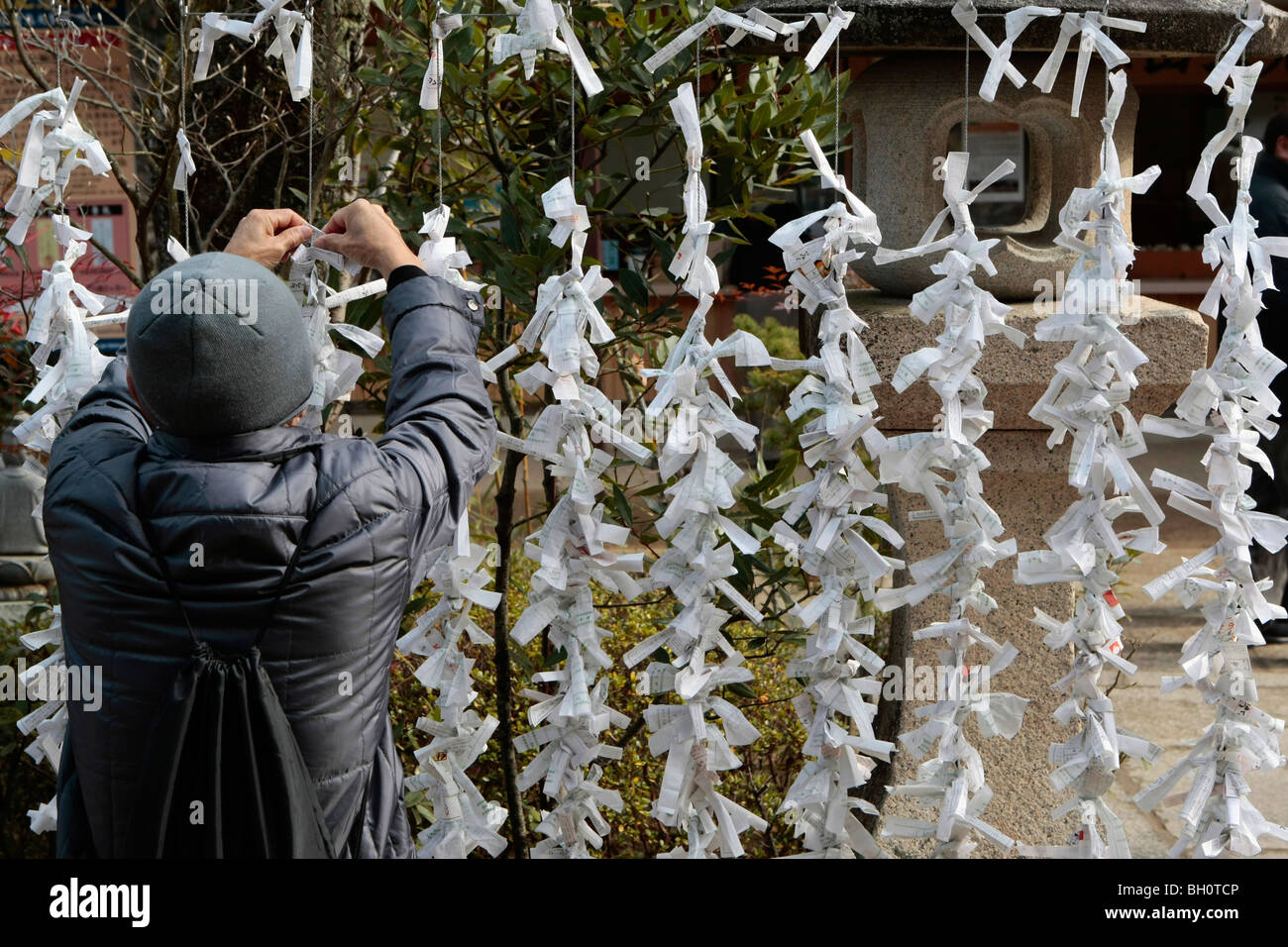 Un uomo cravatte una buona fortuna richieste da una recinzione in un tempio  buddista a Kyoto, in Giappone Foto stock - Alamy