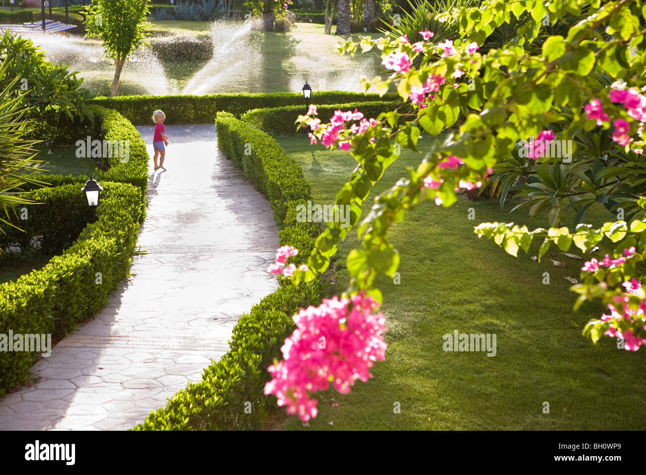 Piccolo bambino, ragazza, passeggiando per il giardino, fiori, bouganville, nel giardino del Lamaya Resort, Coraya, Marsa Alam, Foto Stock