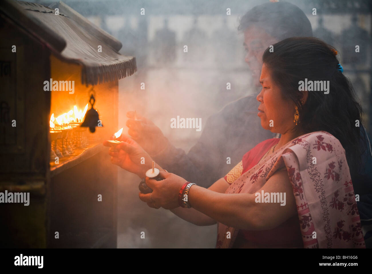 Donna accendendo candele a un santuario, Kathmandu, Nepal Foto Stock