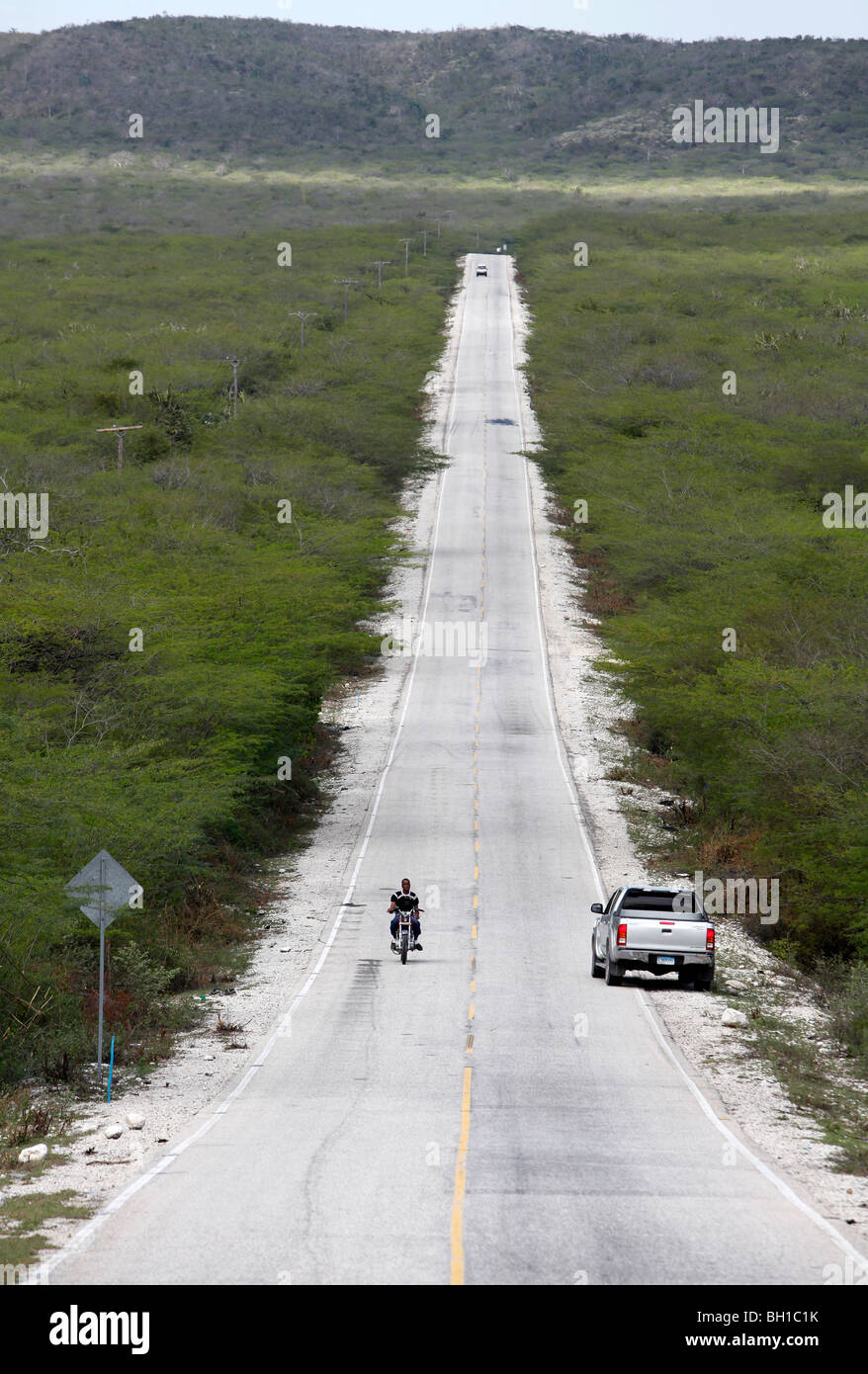 Una strada attraversa un paesaggio arido nel sud-ovest della Repubblica Dominicana Foto Stock