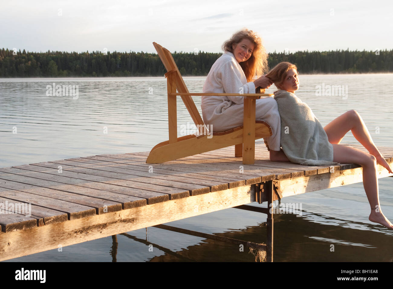 Donna seduta in sedia a sdraio non i capelli della donna seduta sul dock, Clear Lake, Manitoba, Canada Foto Stock